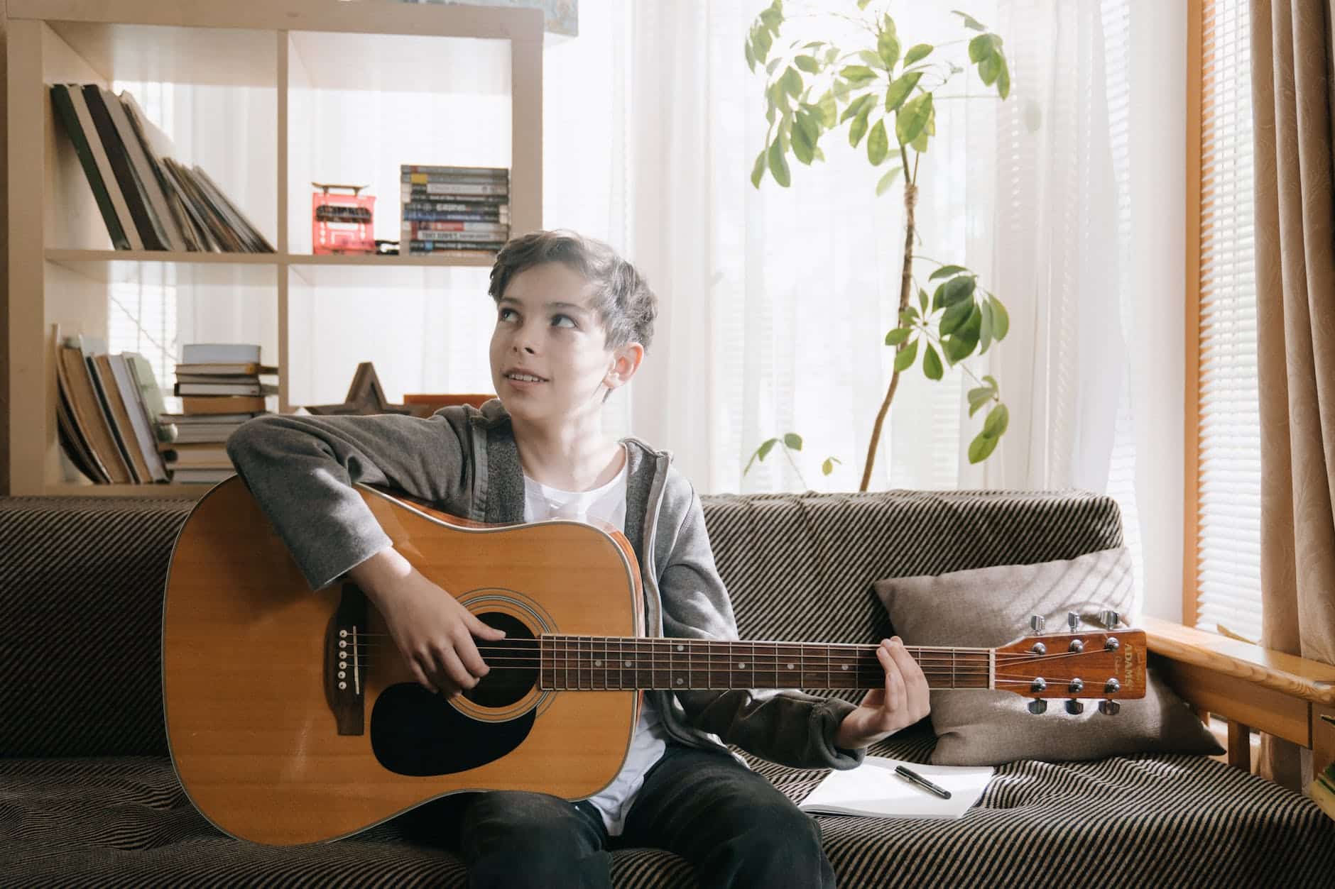 man in black jacket playing acoustic guitar